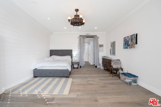 bedroom with an inviting chandelier, ornamental molding, and light wood-type flooring