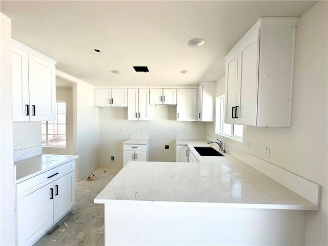 kitchen with white cabinetry, kitchen peninsula, sink, and plenty of natural light