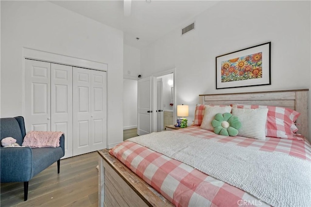 bedroom featuring hardwood / wood-style flooring, a towering ceiling, a closet, and ceiling fan