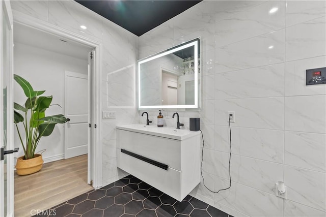 bathroom with a shower, tile walls, wood-type flooring, and vanity