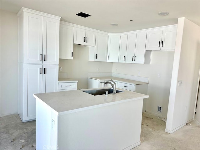 kitchen featuring a kitchen island with sink, sink, and white cabinetry