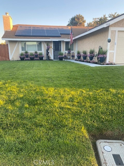 ranch-style house with solar panels, a front lawn, and a garage