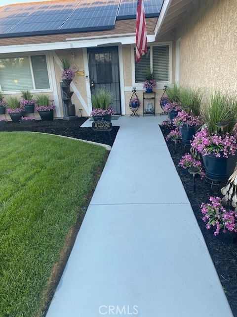 entrance to property with solar panels and a lawn