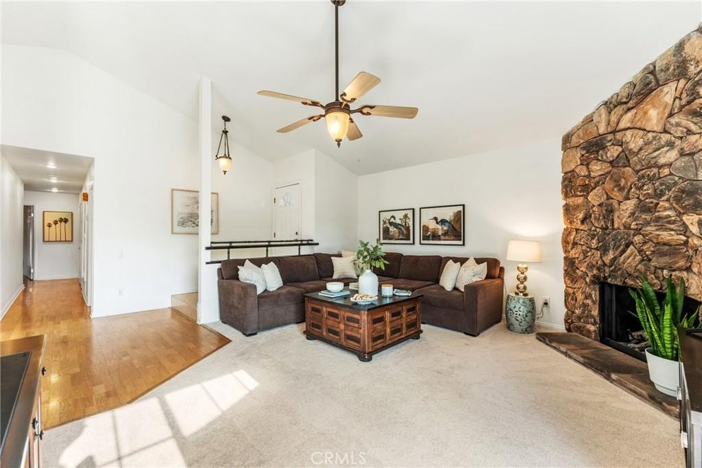 carpeted living room with ceiling fan, high vaulted ceiling, and a fireplace