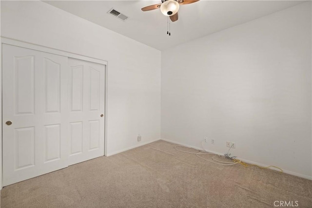 unfurnished bedroom featuring light carpet, a closet, and ceiling fan