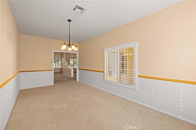 carpeted empty room featuring a healthy amount of sunlight and a notable chandelier