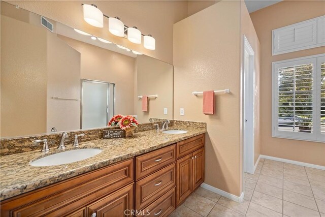 bathroom featuring tile patterned floors, a shower with door, and vanity