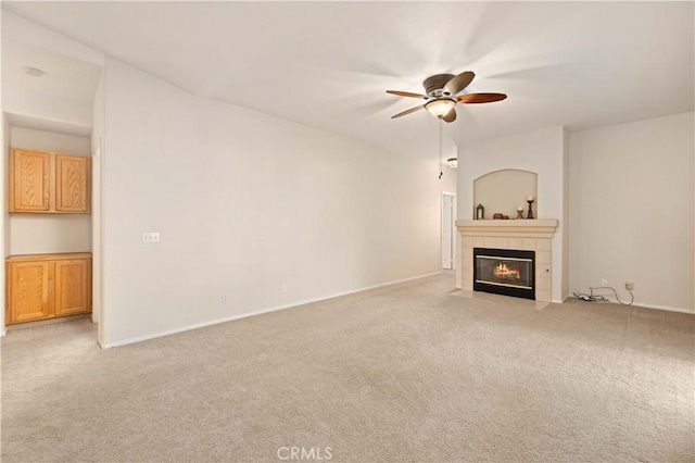 unfurnished living room with ceiling fan, light colored carpet, and a fireplace