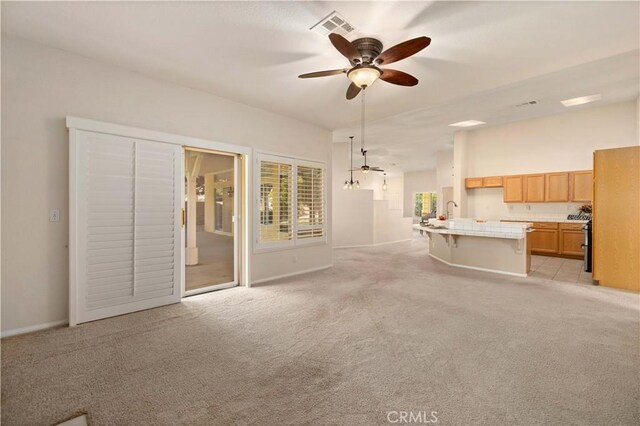 unfurnished living room with light colored carpet, ceiling fan, and sink