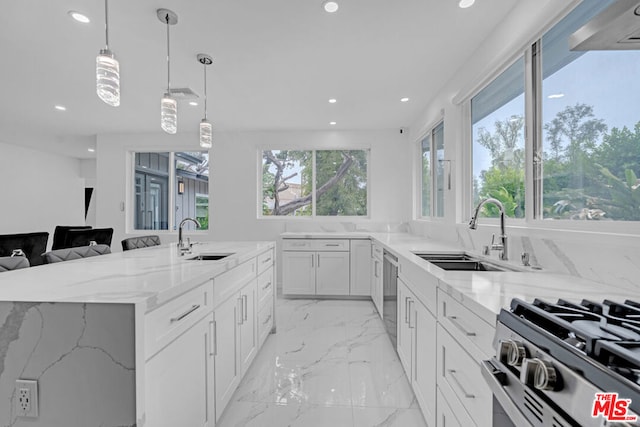 kitchen featuring light stone countertops, sink, white cabinetry, and decorative light fixtures