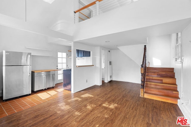 unfurnished living room featuring a towering ceiling and dark hardwood / wood-style flooring