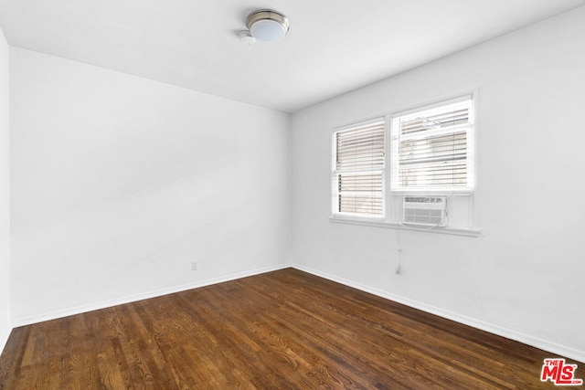 empty room featuring cooling unit and dark hardwood / wood-style flooring