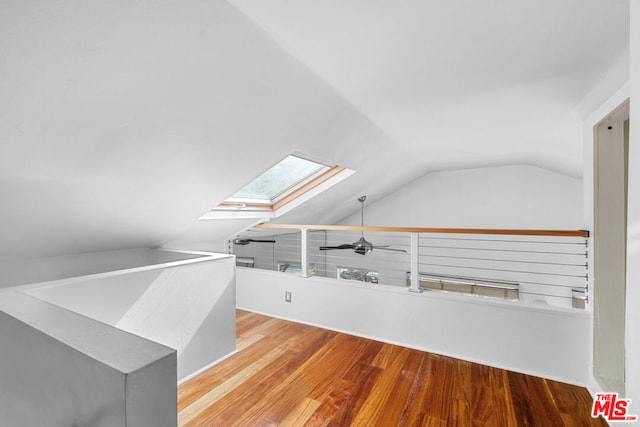 additional living space with lofted ceiling with skylight, light hardwood / wood-style floors, and ceiling fan