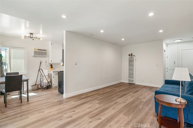 sitting room with an AC wall unit, a notable chandelier, and light hardwood / wood-style floors