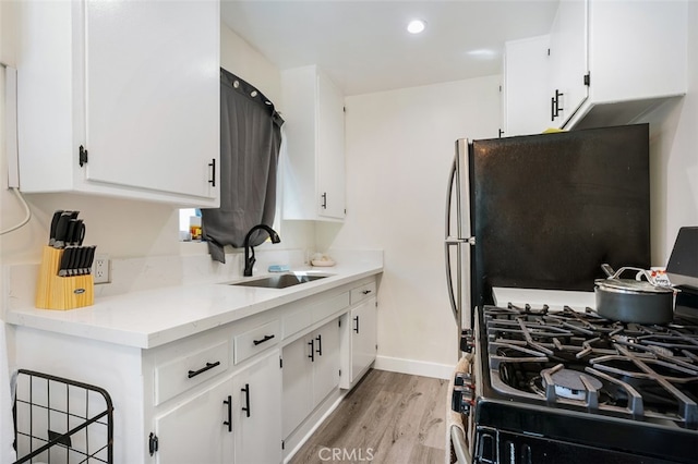 kitchen with white cabinets, sink, and light wood-type flooring