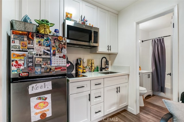 kitchen with sink, white cabinets, stainless steel appliances, and dark hardwood / wood-style floors