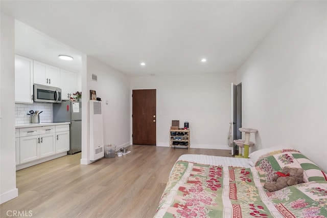 bedroom featuring stainless steel refrigerator and light hardwood / wood-style flooring