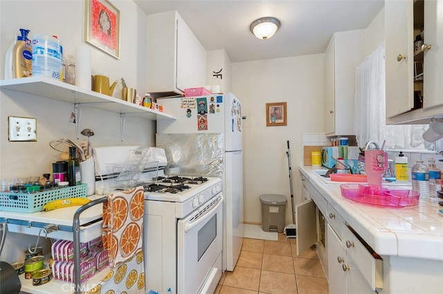 kitchen with white cabinetry, tile countertops, light tile patterned floors, and gas range gas stove