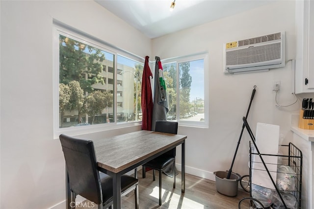 dining space with light hardwood / wood-style floors and a wall unit AC