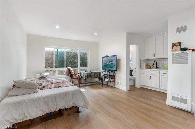 bedroom with light hardwood / wood-style flooring and ensuite bathroom