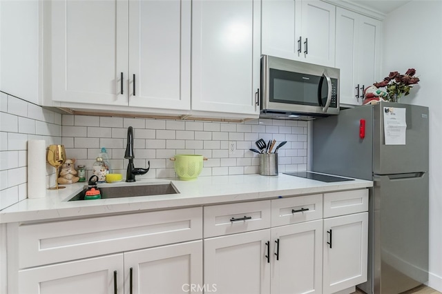 kitchen featuring white cabinets, light stone countertops, stainless steel appliances, and sink