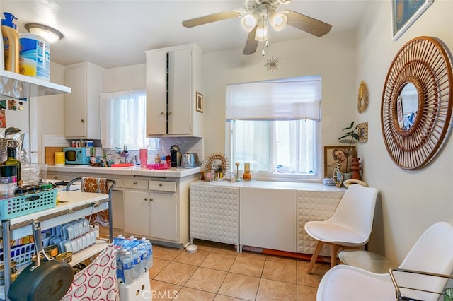 kitchen featuring tasteful backsplash, ceiling fan, light tile patterned floors, white cabinetry, and tile counters