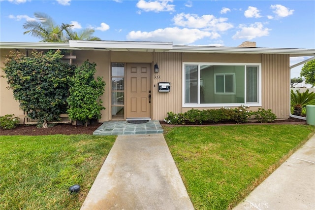 view of exterior entry with a yard