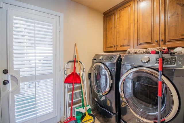 clothes washing area featuring a wealth of natural light, washer and dryer, and cabinets