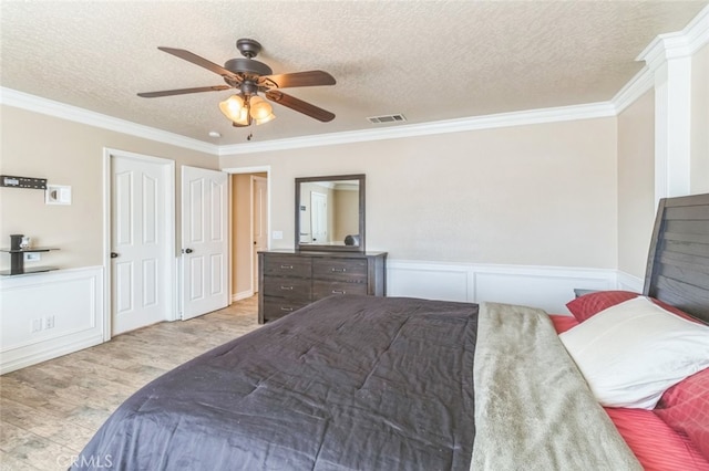 bedroom with ornamental molding, light hardwood / wood-style flooring, a textured ceiling, and ceiling fan