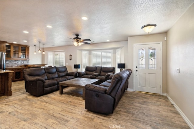 living room featuring a textured ceiling, hardwood / wood-style flooring, and ceiling fan