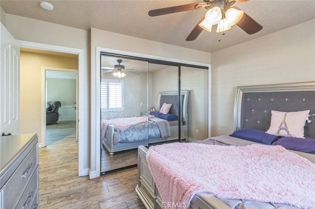 bedroom with a closet, light hardwood / wood-style floors, and ceiling fan