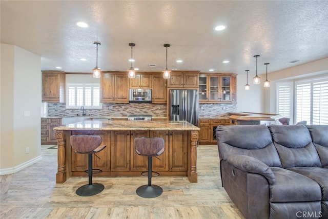 kitchen featuring appliances with stainless steel finishes, a center island, hanging light fixtures, and a wealth of natural light