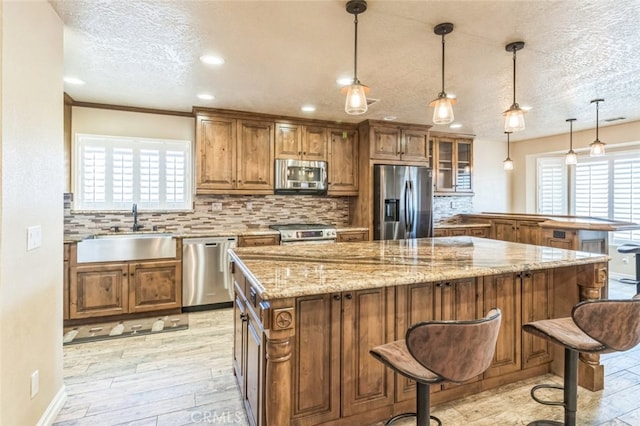 kitchen featuring decorative backsplash, a textured ceiling, sink, light hardwood / wood-style floors, and stainless steel appliances