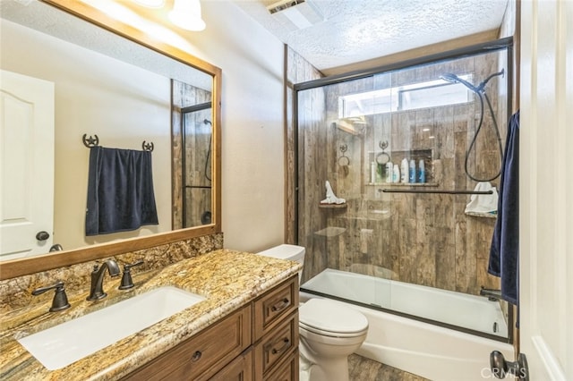 full bathroom with bath / shower combo with glass door, a textured ceiling, hardwood / wood-style flooring, toilet, and vanity