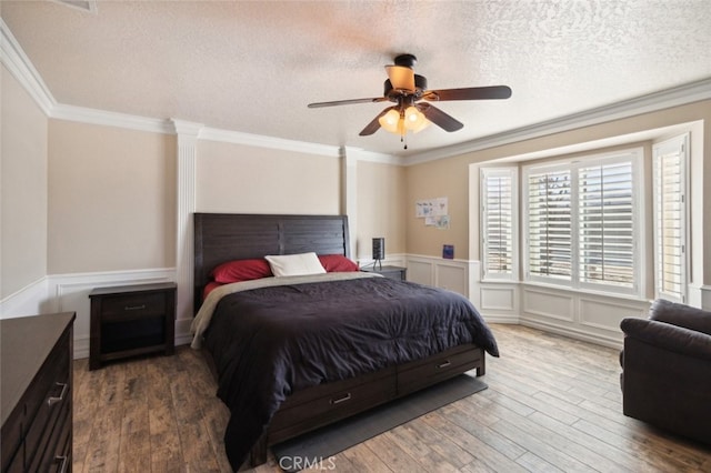 bedroom with ceiling fan, hardwood / wood-style flooring, ornamental molding, and a textured ceiling