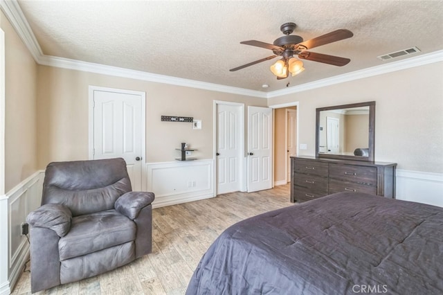 bedroom featuring ceiling fan, a textured ceiling, ornamental molding, and light wood-type flooring