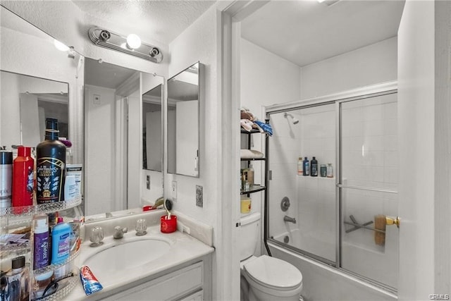 full bathroom with vanity, combined bath / shower with glass door, a textured ceiling, and toilet