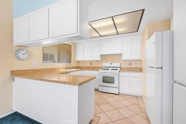 kitchen with light tile patterned floors, kitchen peninsula, white appliances, and white cabinetry