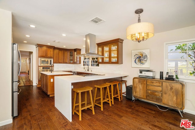 kitchen with island range hood, kitchen peninsula, decorative backsplash, dark hardwood / wood-style floors, and hanging light fixtures