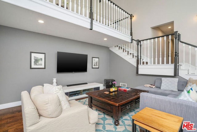 living room with a high ceiling and dark hardwood / wood-style floors