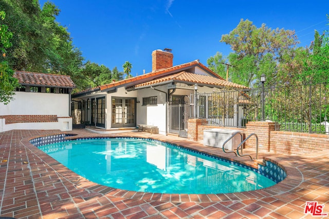 view of swimming pool with french doors and a patio area