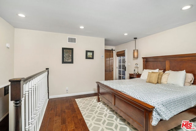 bedroom featuring dark wood-type flooring and a barn door