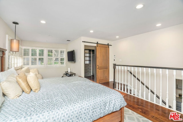 bedroom featuring wood-type flooring and a barn door