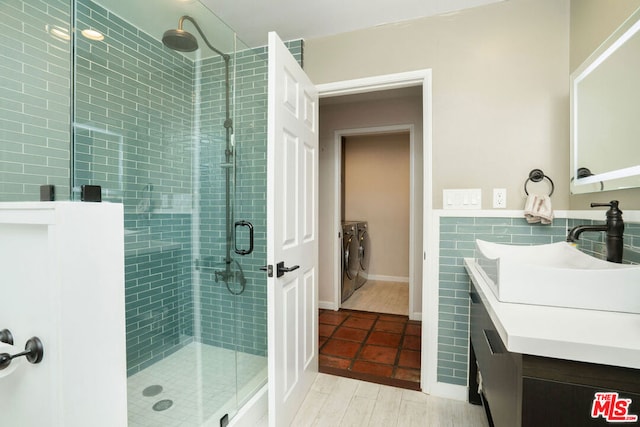 bathroom with tile walls, independent washer and dryer, an enclosed shower, and vanity