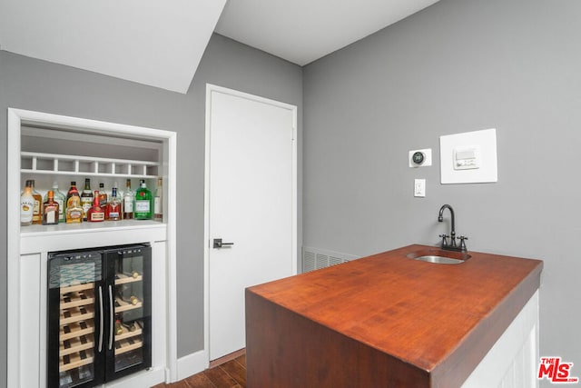 bar featuring dark wood-type flooring, beverage cooler, and sink