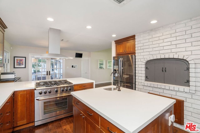 kitchen featuring island exhaust hood, stainless steel appliances, a kitchen island with sink, dark hardwood / wood-style flooring, and sink