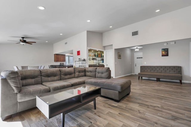 living room featuring hardwood / wood-style flooring, a towering ceiling, and ceiling fan