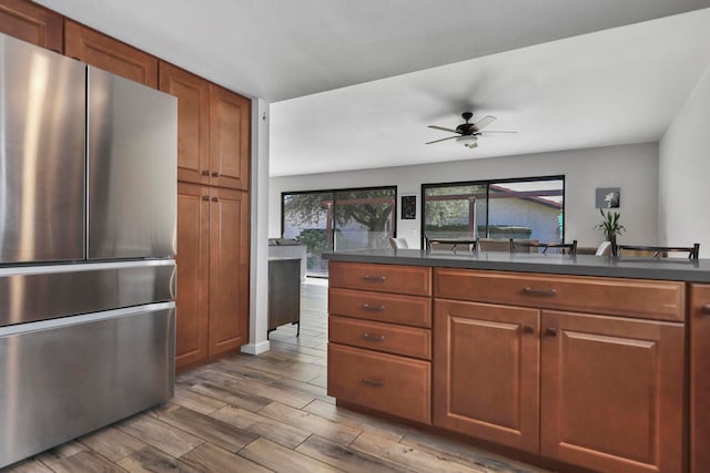 kitchen featuring stainless steel fridge, light hardwood / wood-style flooring, and ceiling fan