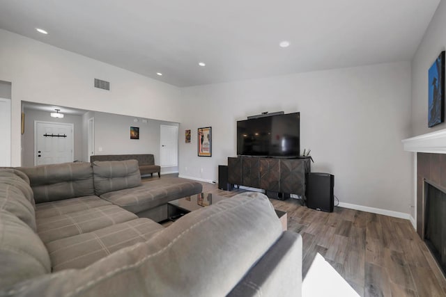 living room with wood-type flooring and a tile fireplace