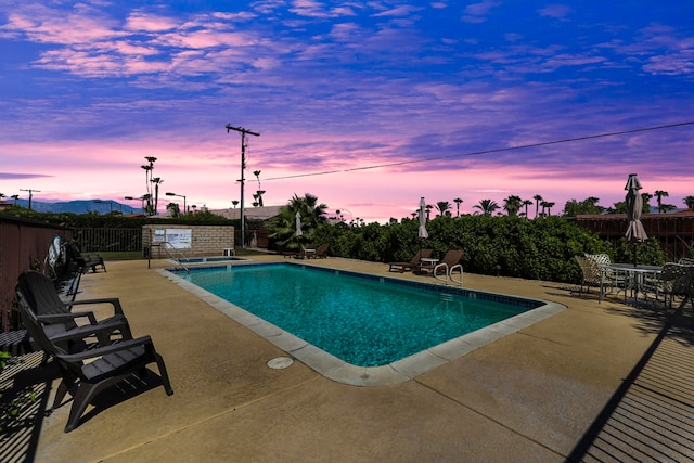 pool at dusk featuring a patio area